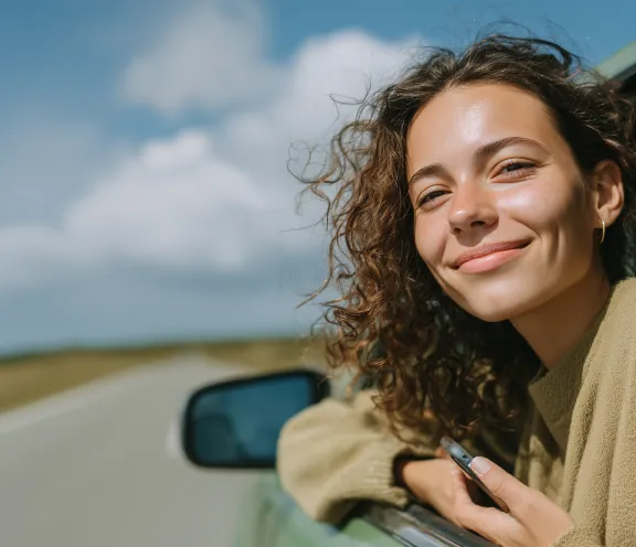 Woman leaning out of a car window smiling