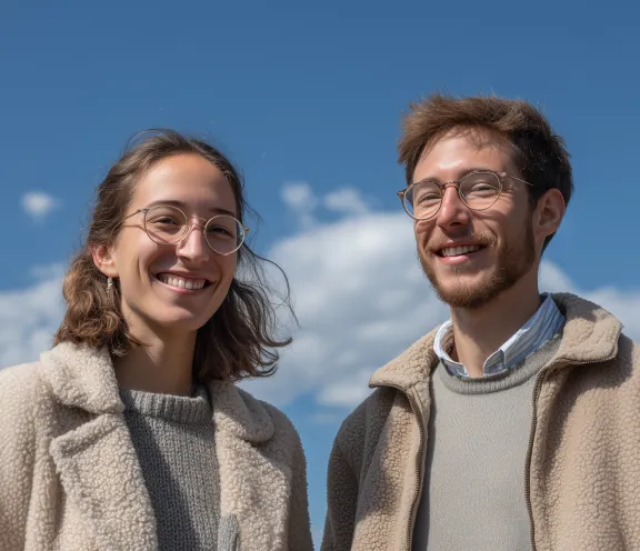 Two colleagues smiling against a blue sky