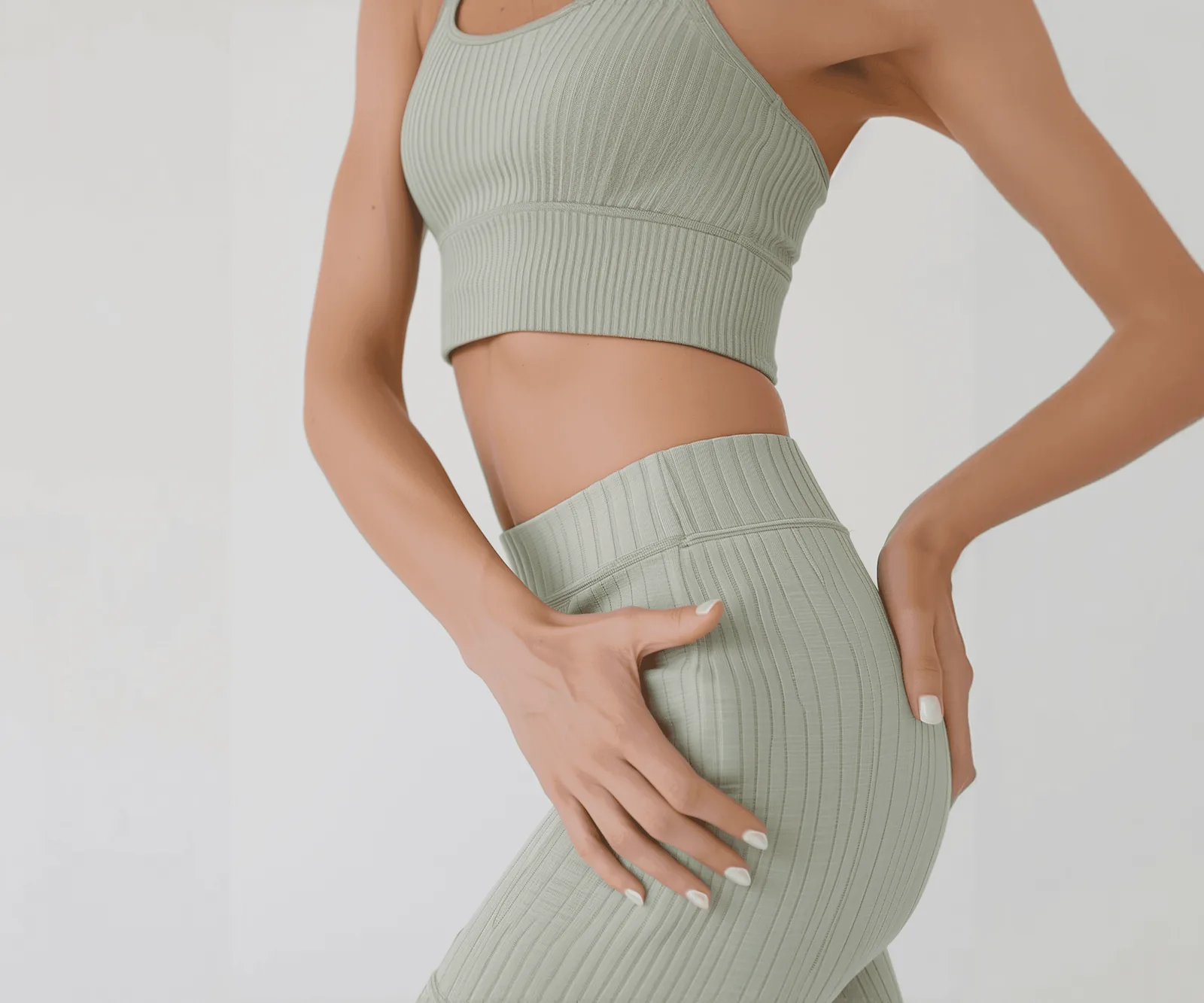Woman in sage green activewear against a white background