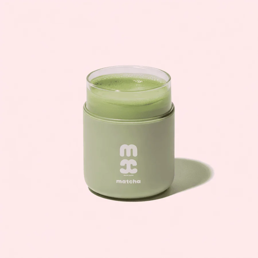 Classic iced matcha in a green reusable cup on a soft pink background